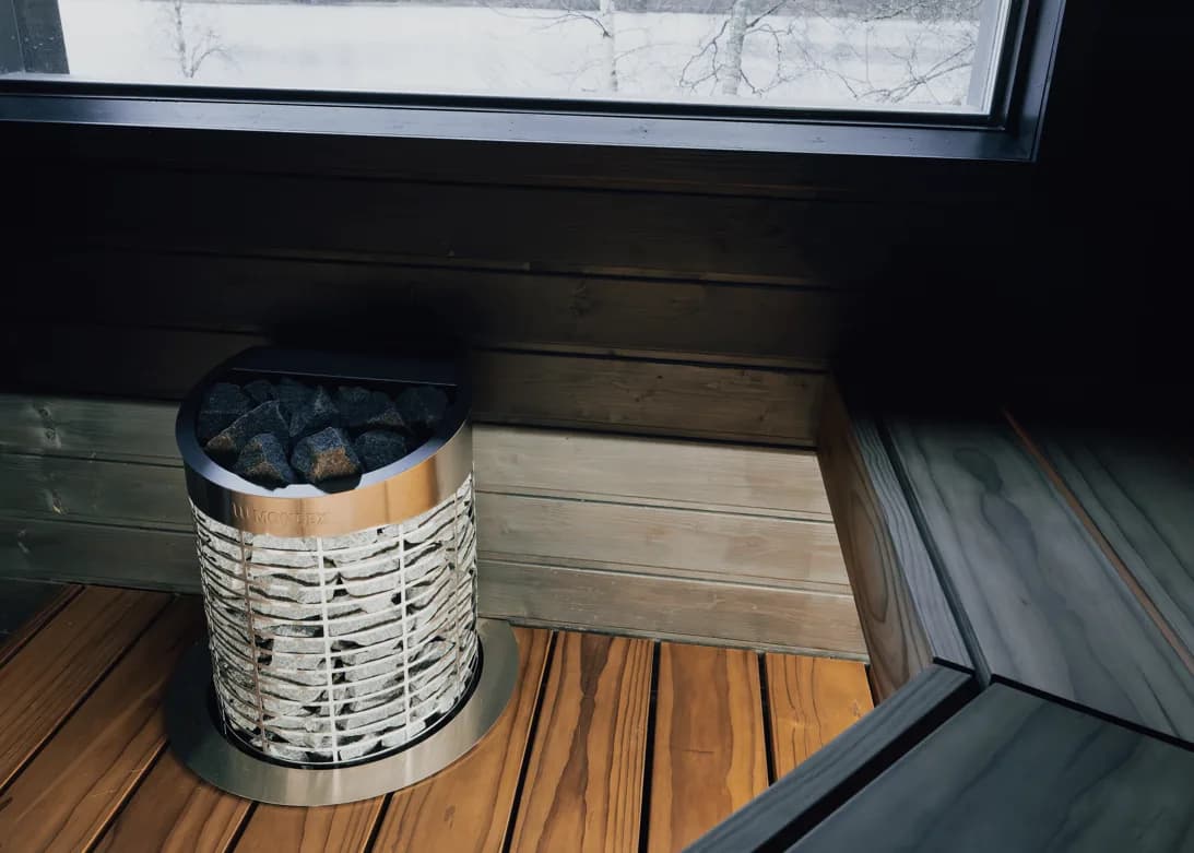 Mondex Kalla 2.0 heater in a wooden sauna with snowy birch trees through the window