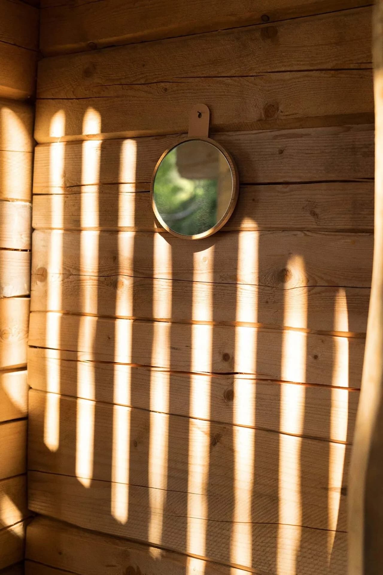 Sunlight streaming through sauna window, casting warm lines on wooden walls